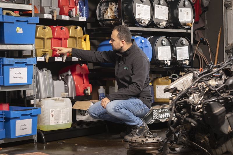 Adviseur van Prevensa wijst op de opslag van koelvloeistoffen en oliën in een werkplaats