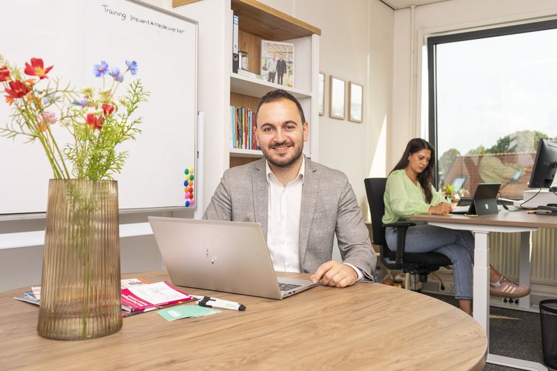 Adviseur van Prevensa aan tafel op kantoor, met een collega op de achtergrond